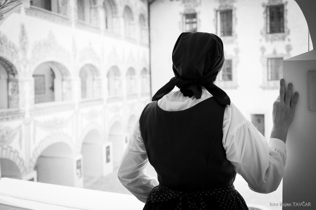 Fotografija: Na črno-beli fotografiji igralka stoji na balkonu gradu, slikana je od zadaj, oblečena je v belo bluzo čez katero ima temno obleko brez rokavov, črn predpasnik z belimi rožicami, na glavi ima zadaj zavezano črno ruto. Z desno roko se dotika stebra in zre v daljavo.